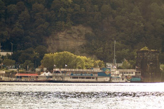 pexels-photo-28610553-28610553 Classic riverboat docked by lush green cliffs in Pittsburgh, PA.