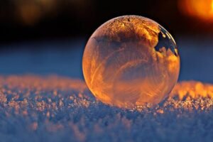 pexels-photo-302743-302743-1 Close-up shot of a frozen bubble with warm reflections resting on a snowy surface at twilight.